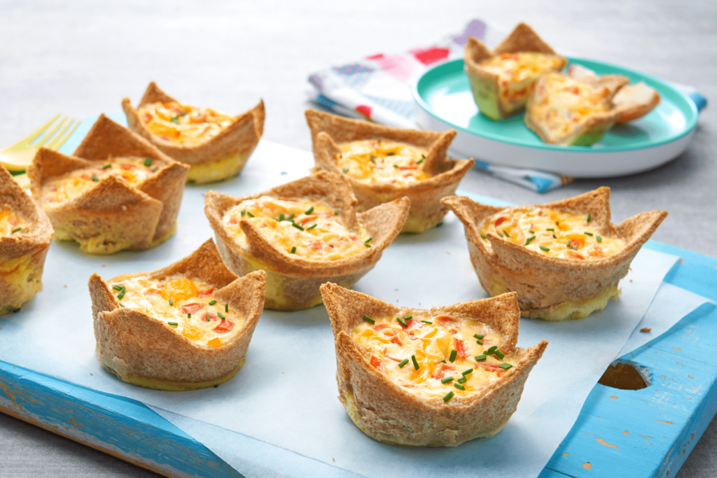 Freshly baked egg bread cups on a blue chopping board