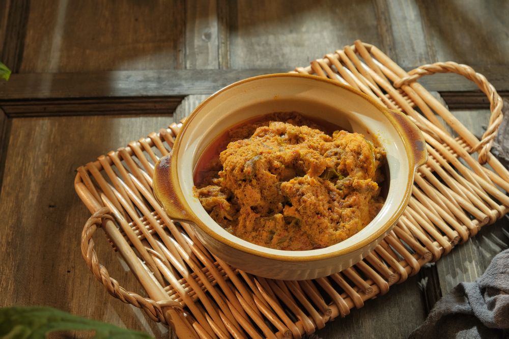 Ayam rendang dihidangkan di dalam mangkuk tanah liat diletakkan di atas dulang raga